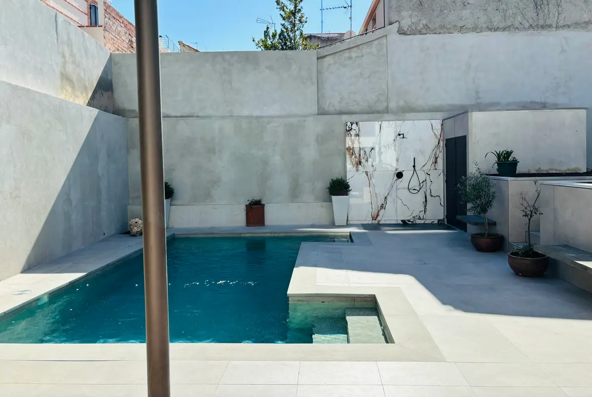 Piscina en el patio, con muros de hormigón y mármol.