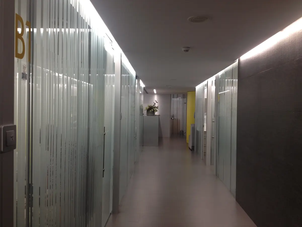Pasillo de la clínica con vidrio acanalado y luz lineal.