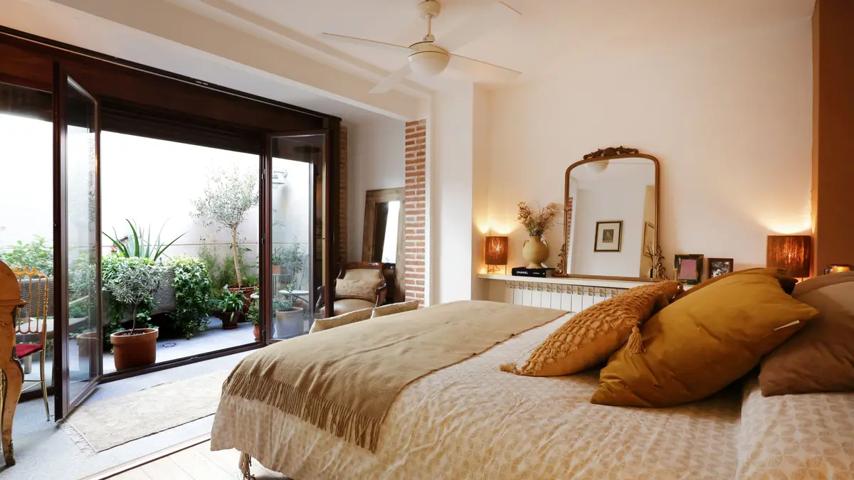 Dormitorio con cama en tonos arena.