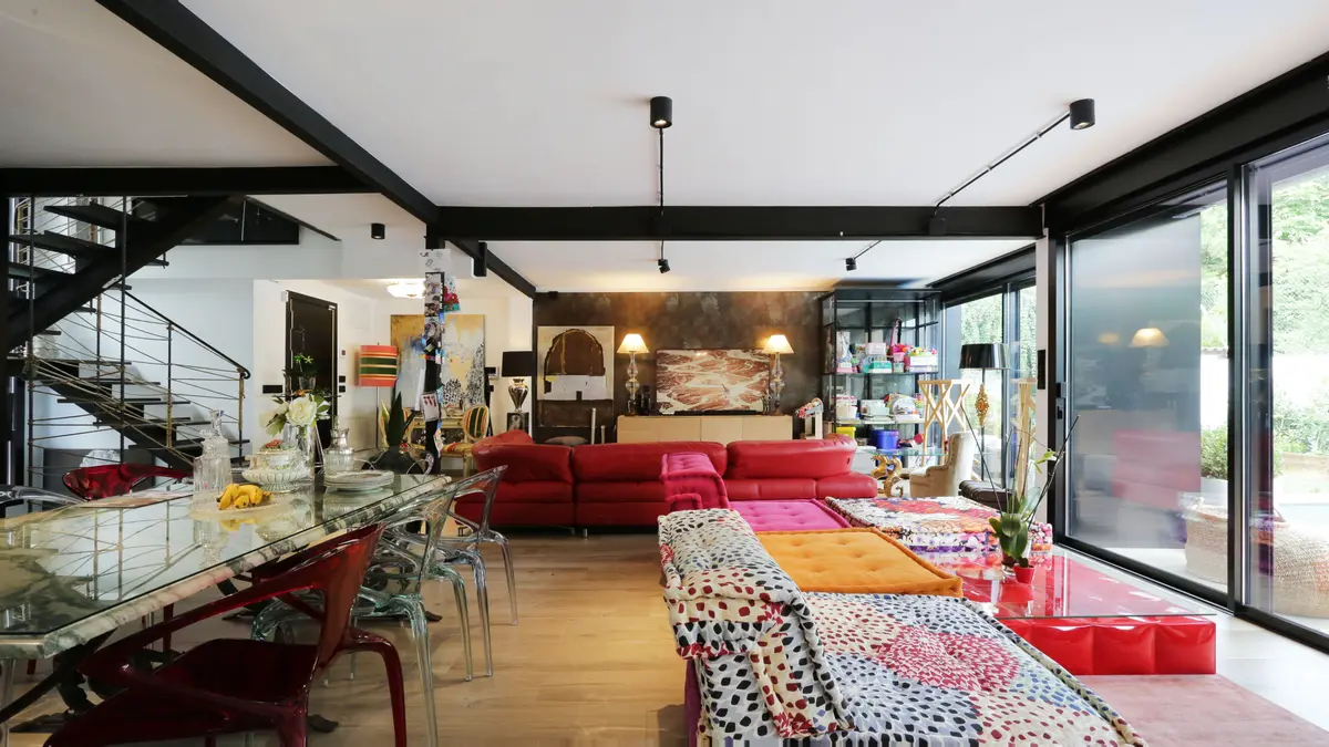 Salón de doble altura con sofás rojos y estructura de acero vista.