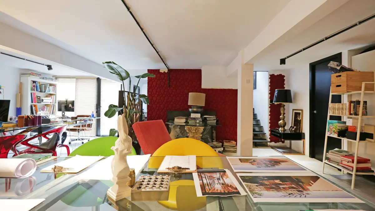 Zona de trabajo con mesa de cristal y pared roja.