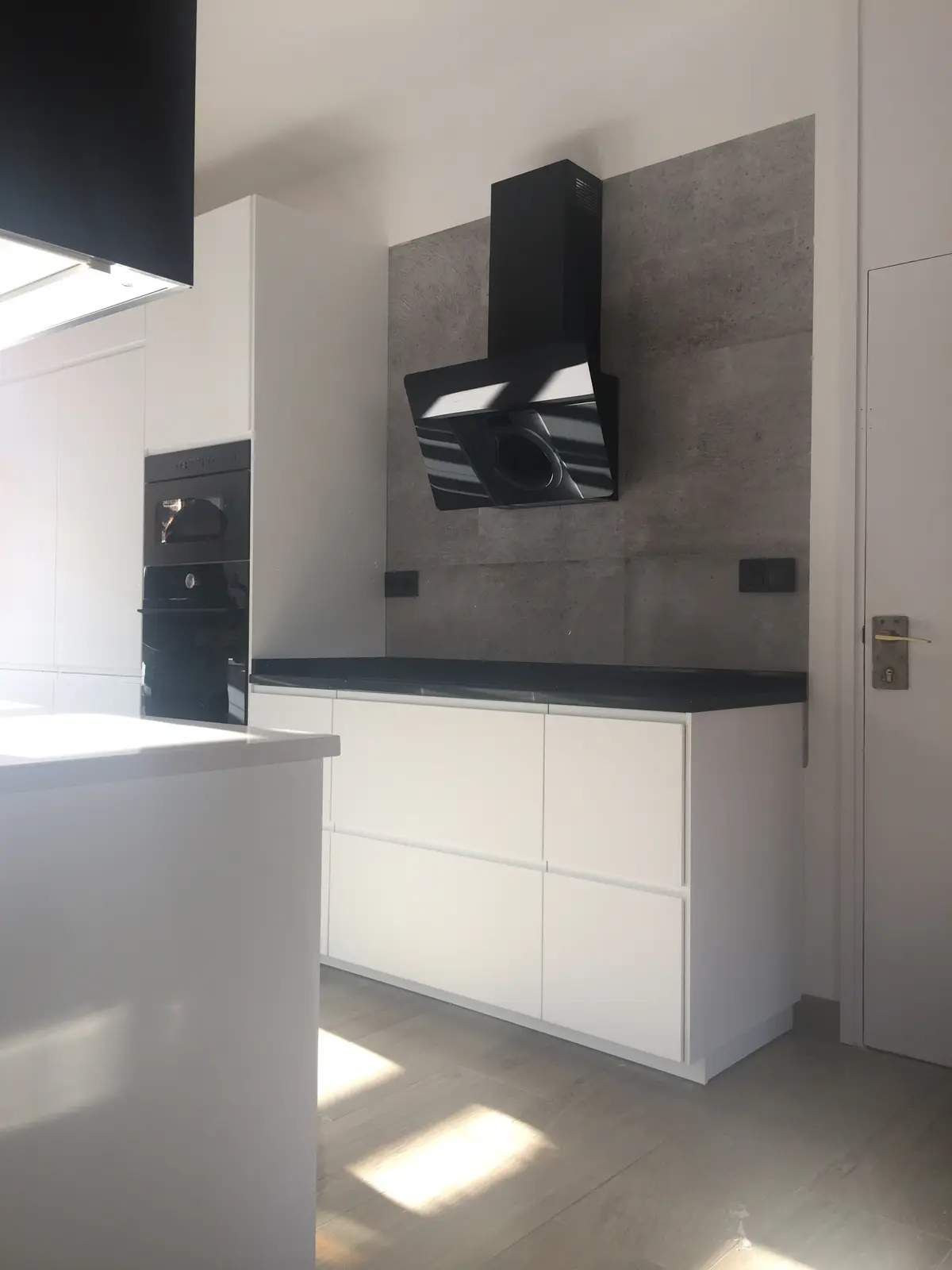 Cocina blanca con campana negra.