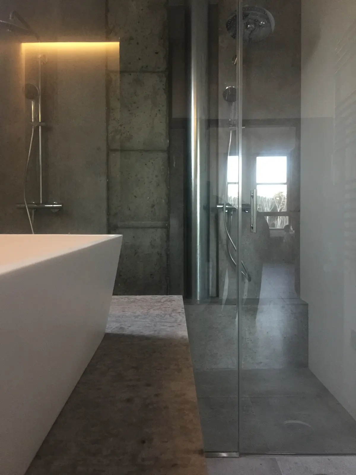Baño con bañera exenta y ducha de hormigón.